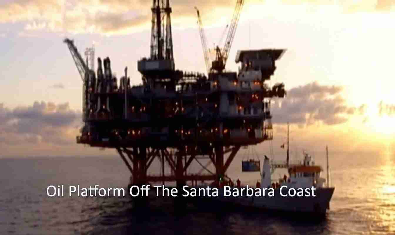 Offshore oil platform off the Santa Barbara coast with a support boat nearby at sunset.