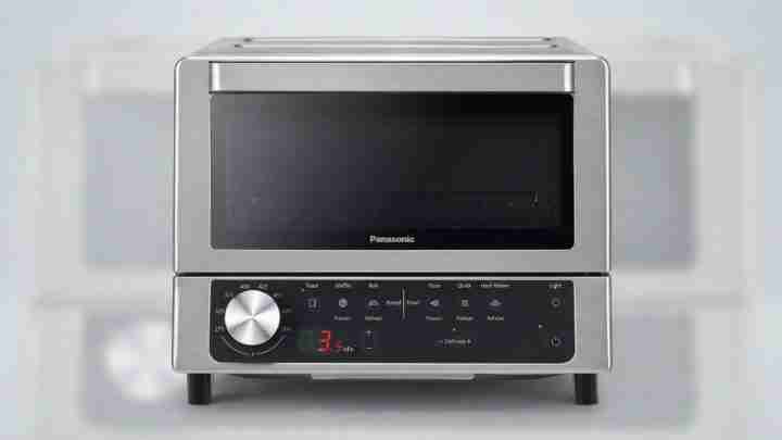 Stainless steel Panasonic countertop oven with a large front door and knob controls on a black panel below the door.