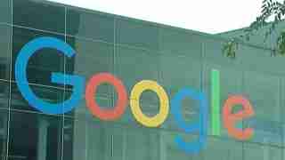 Google logo on a glass building façade with large colored letters in blue, red, yellow, green, spelling 'Google'.