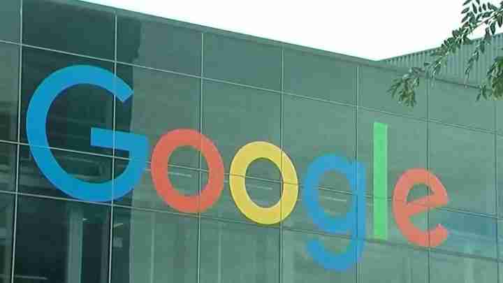 Google logo on a glass building façade with large colored letters in blue, red, yellow, green, spelling 'Google'.