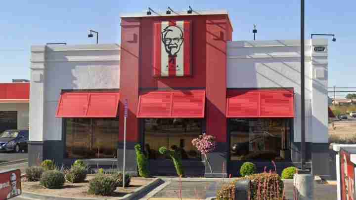 KFC fast-food restaurant with red facade, large Colonel Sanders sign, and red awnings over the windows in front.